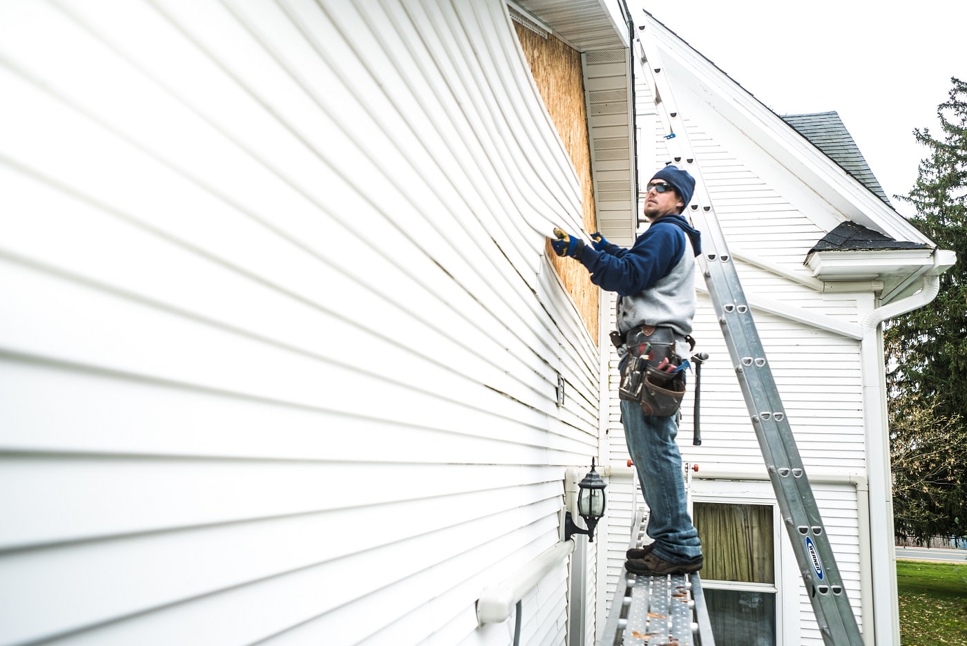 Worker on scaffolding installing new siding on a home
