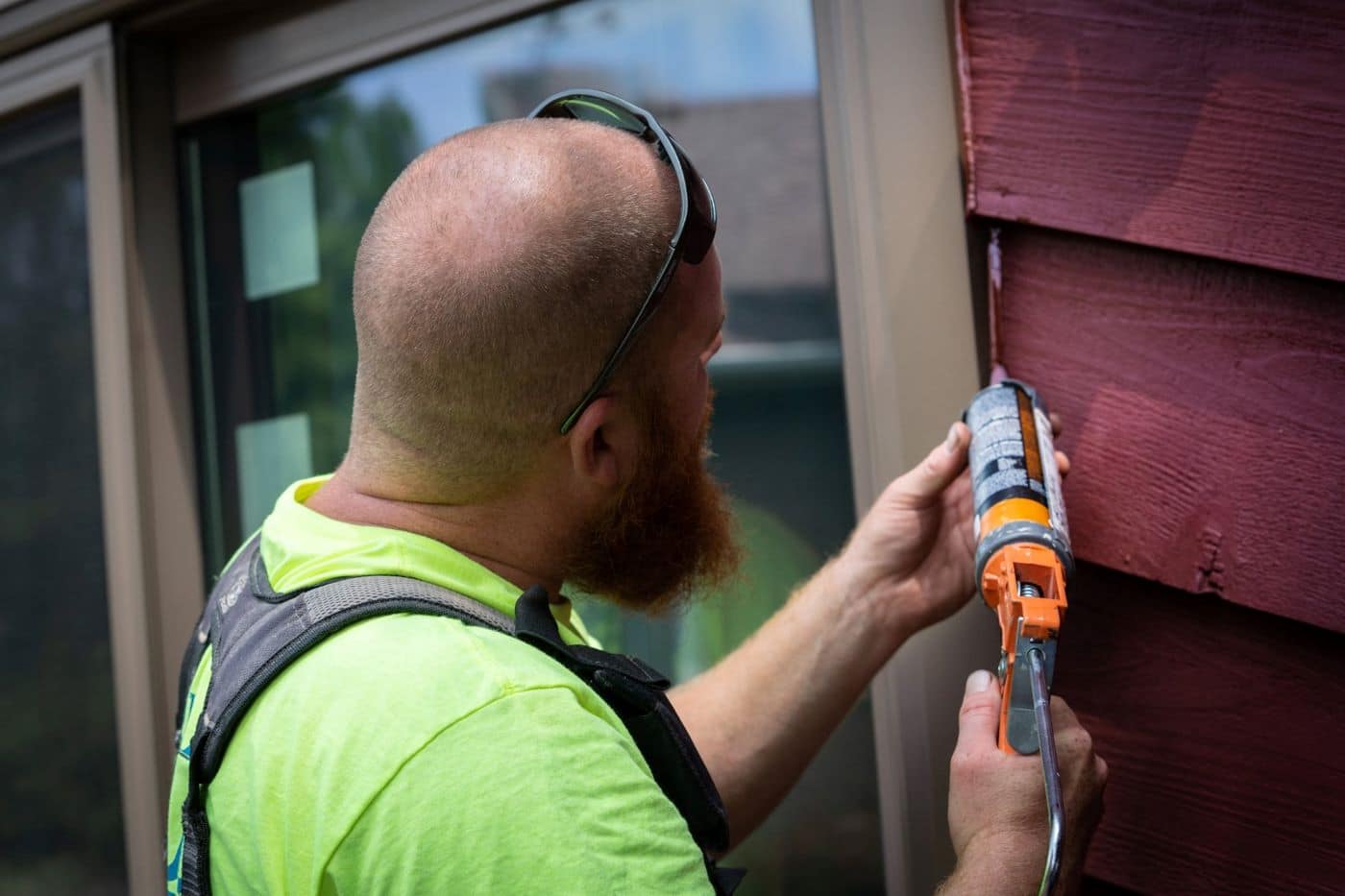 Caulk installation on a home with red siding.